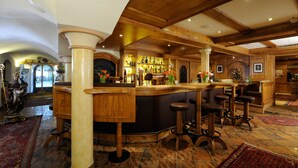 A bar area with wooden bar stools, a central bar counter, and a decorative statue. - Hotel Bierwirt (Innsbruck)