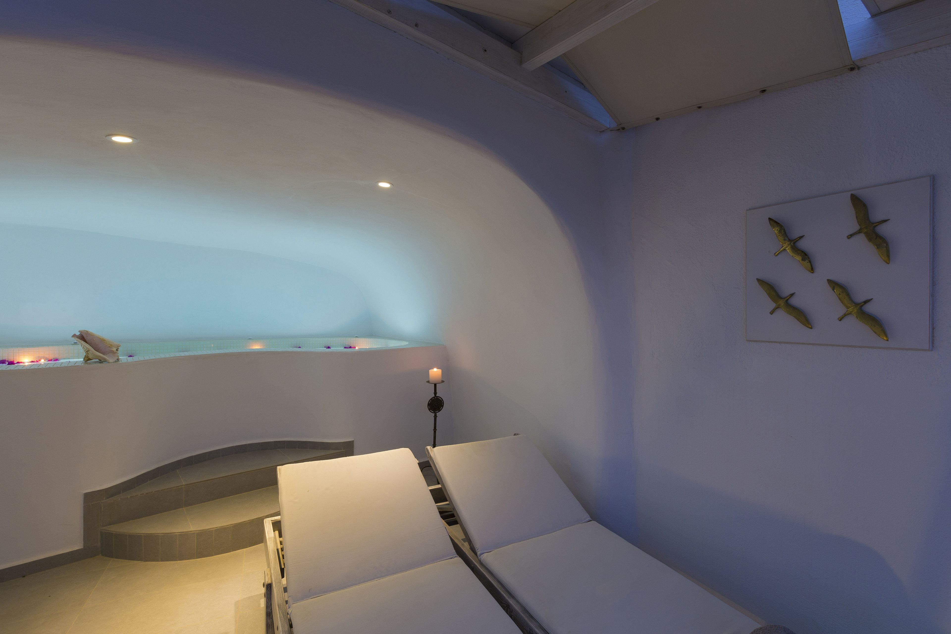 A spa room with a curved ceiling, a bathtub, and a wall-mounted bird sculpture.