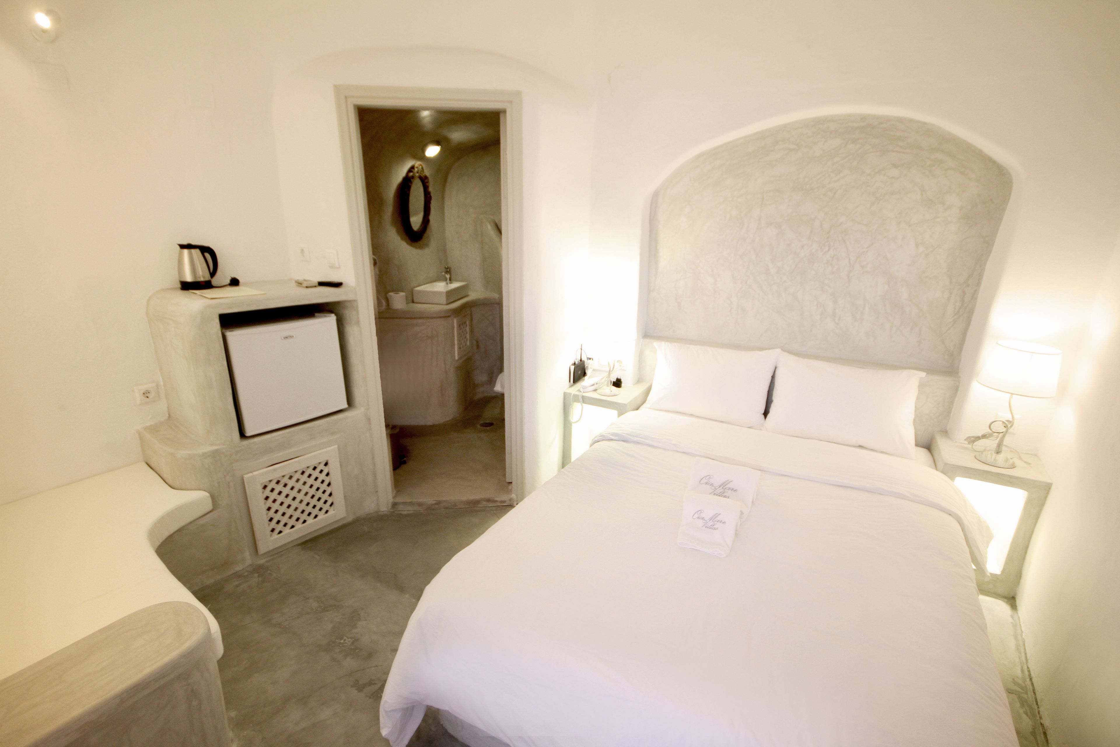 Una habitación de hotel con cama, escritorio, kitchenette pequeña y baño.