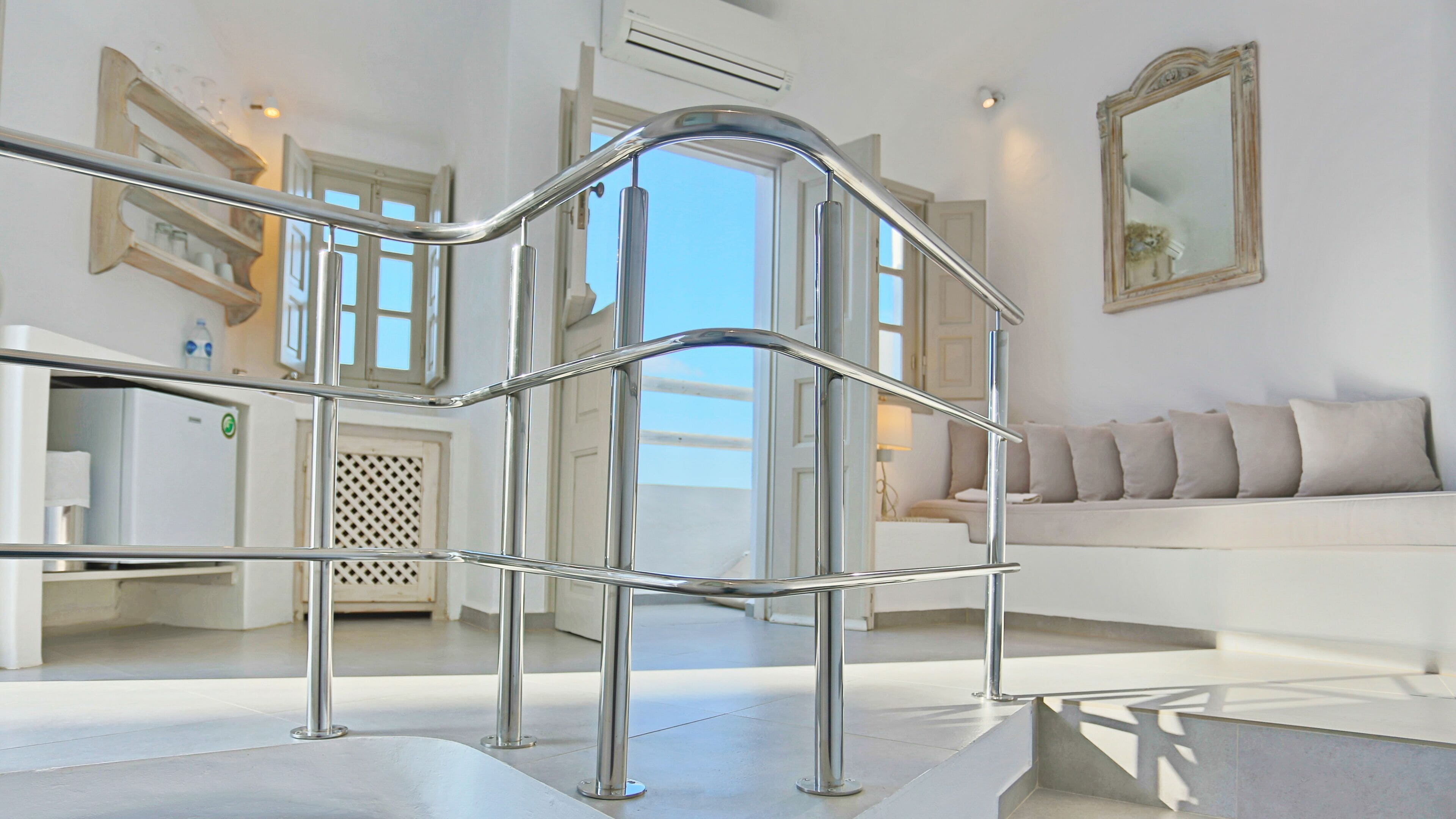 A modern hotel lobby with a central staircase, a sofa set, and a large mirror.