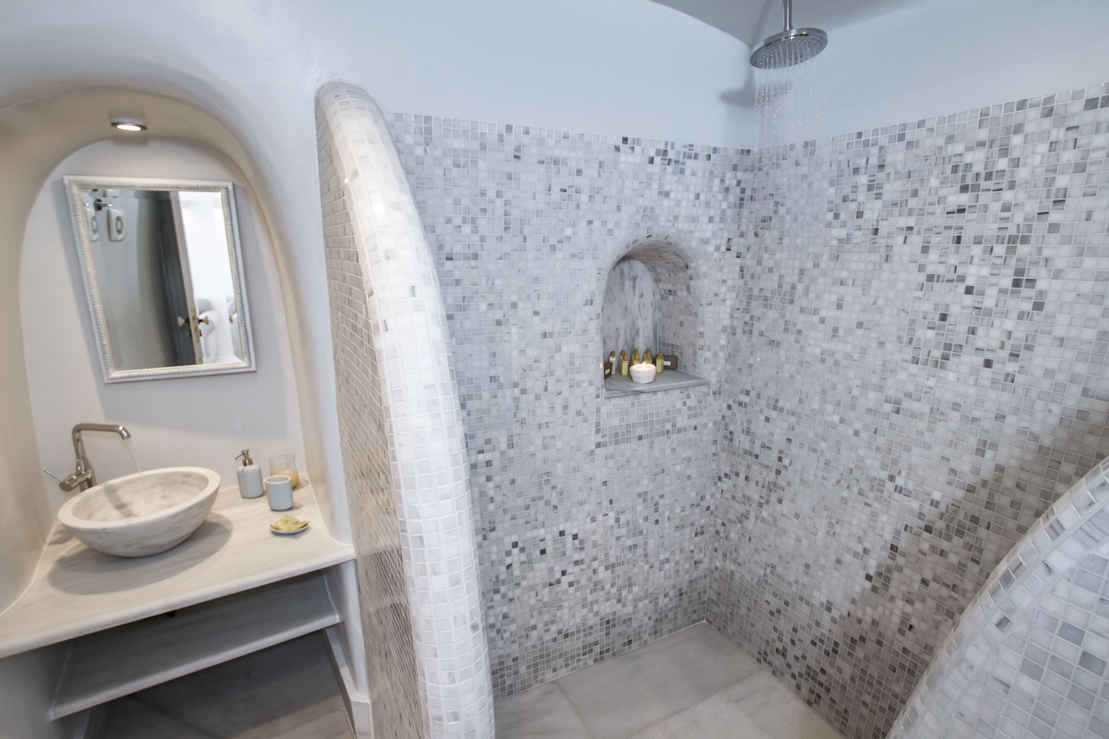A bathroom with a white sink, mirror, and tiled shower area.