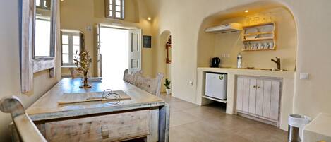 A spacious kitchen with a wooden dining table, white cabinets, and a built-in oven.