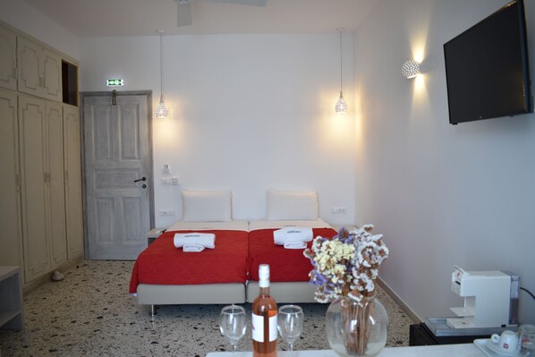 A hotel room with two beds, a minibar, a TV, and a coffee machine.