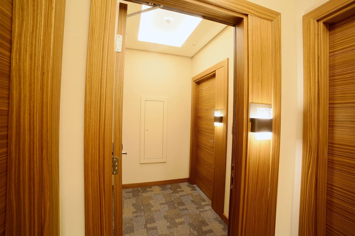 A narrow hallway with wooden doors and a carpeted floor.