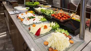 Un bufé con diversos alimentos, incluyendo verduras, quesos y frutas.