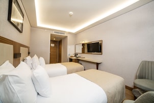 A hotel room with two beds, a desk, a chair, a television, and a mirror.
