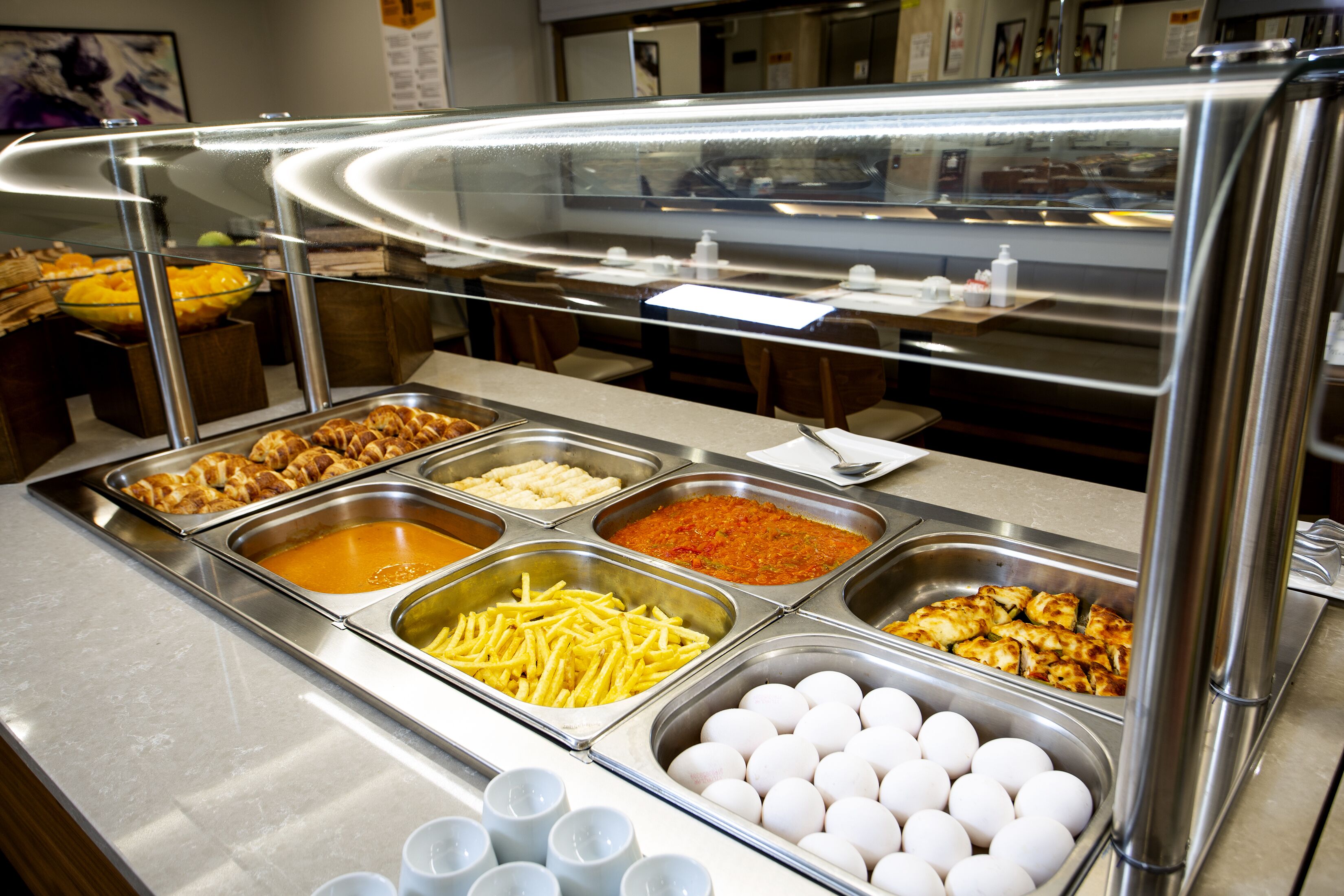 Un bufé con diversos alimentos, como huevos, papas fritas y diferentes salsas.
