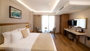 A hotel room with a large bed, a desk, a television, and a window with curtains. - Erboy Hotel (Istanbul)