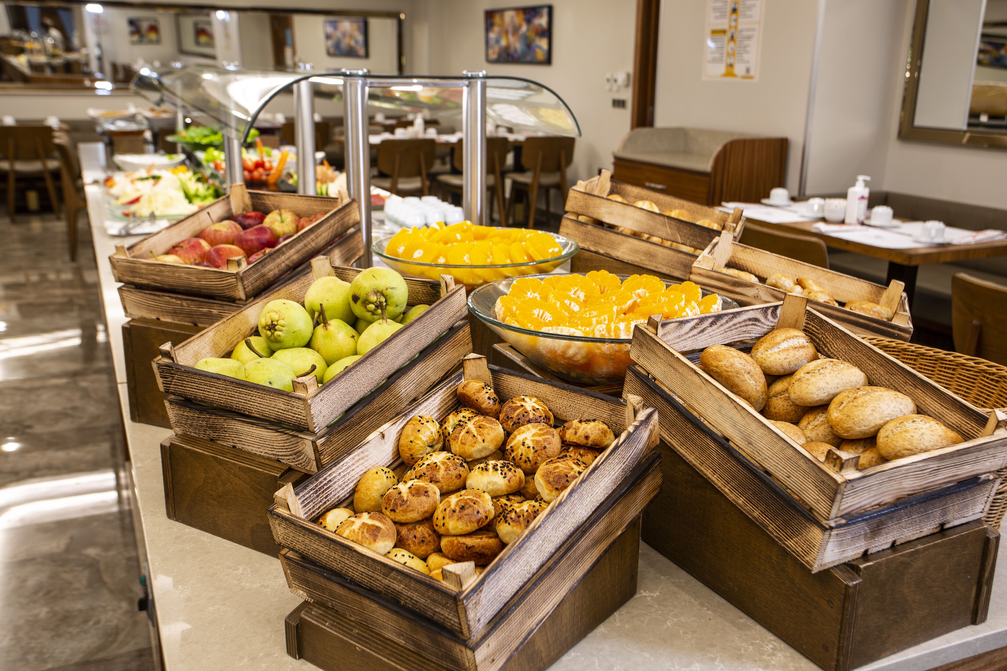Un bufé con diferentes opciones de comida, incluyendo frutas, pan y pasteles.