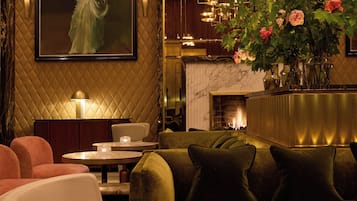 A modern interior with a plush sofa, a white chair, a dining table, and a large framed artwork on the wall.
