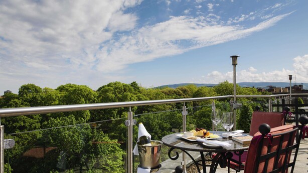 Una terraza con una mesa lista para comer, con vistas a un paisaje verde exuberante y colinas distantes.
