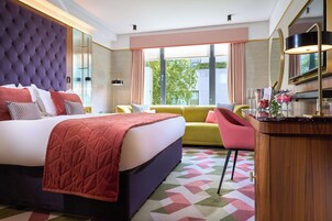 Una habitación de hotel moderna con una cama grande, un sofá, un escritorio con espejo y vistas al exterior.