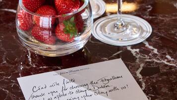 Een tafel met twee champagneglazen, een schaal aardbeien en een bedankbriefje van The Fitzwilliam Hotel.
