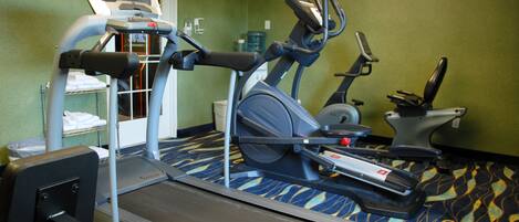 Un gimnasio con cintas de correr, elípticas y una bicicleta estática.
