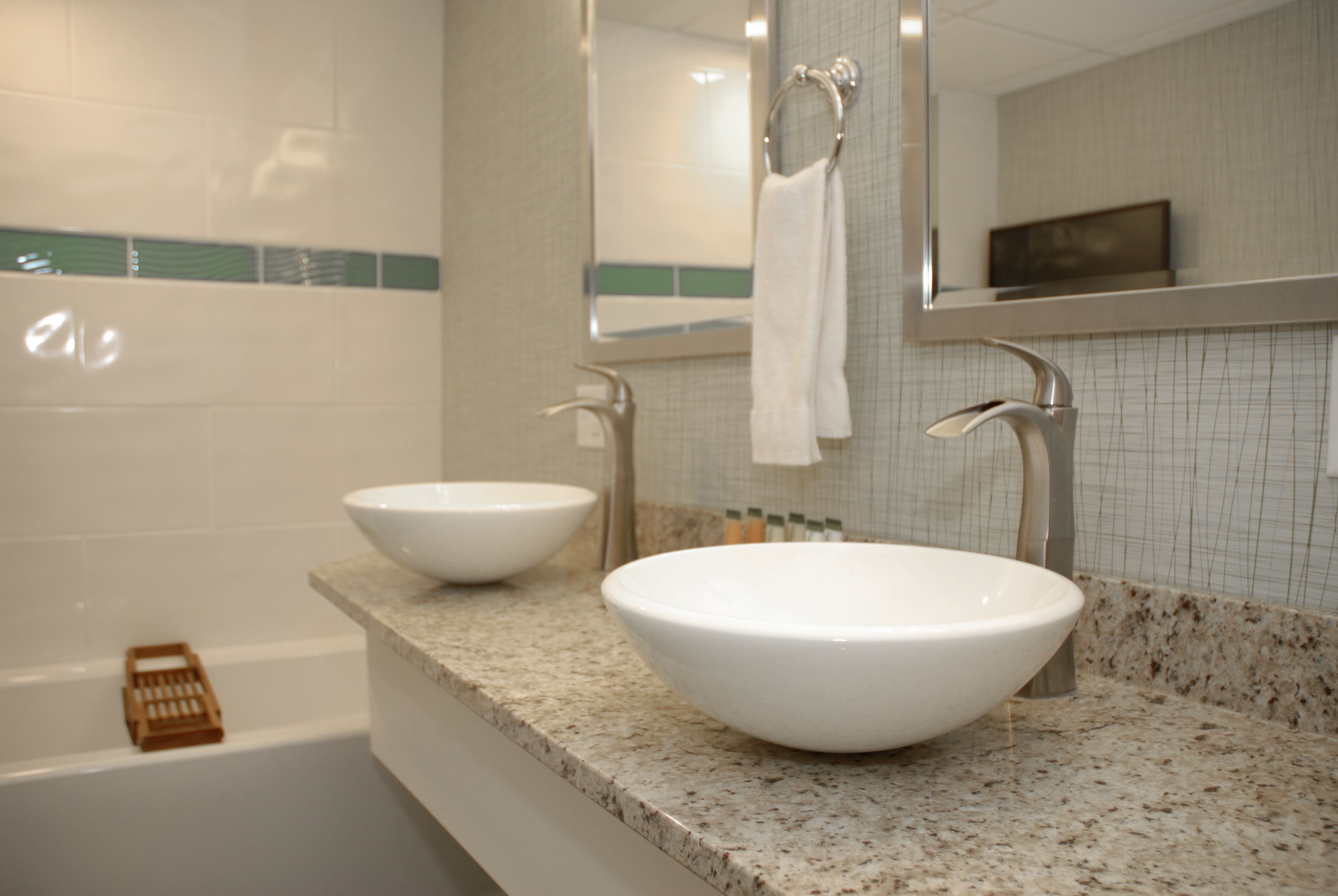 A bathroom with two white sinks, a bathtub, and a mirror above the sinks.