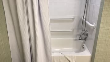 Une salle de bain équipée d’une baignoire, de barres d’appui, d’un pommeau de douche et d’une serviette.