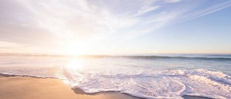 A beach with waves gently lapping onto the shore under a clear sky.