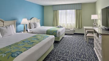A hotel room with two beds, a desk, a dresser, and a window with curtains.