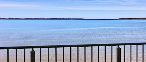 Un balcón con vistas a un mar tranquilo y tierra lejana.