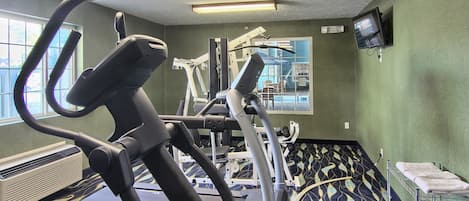 A gym with treadmills, elliptical machines, and a TV on the wall.