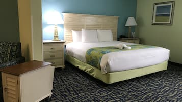 A hotel room with a large bed, a nightstand, a dresser, and a chair.