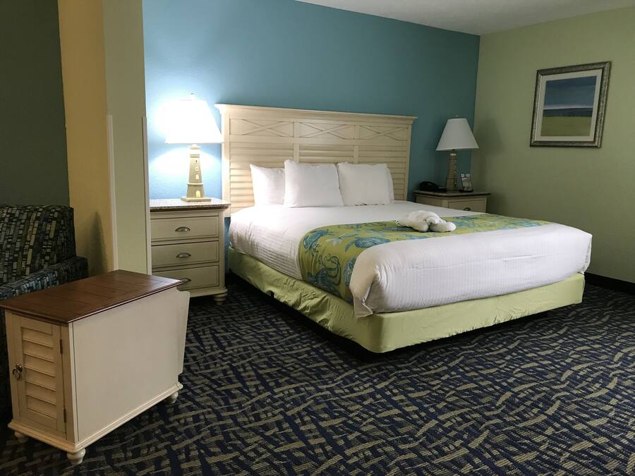 A hotel room with a large bed, a nightstand, a dresser, and a chair.