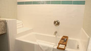 A bathroom with a bathtub, a towel rack, and a wooden tray with toiletries.