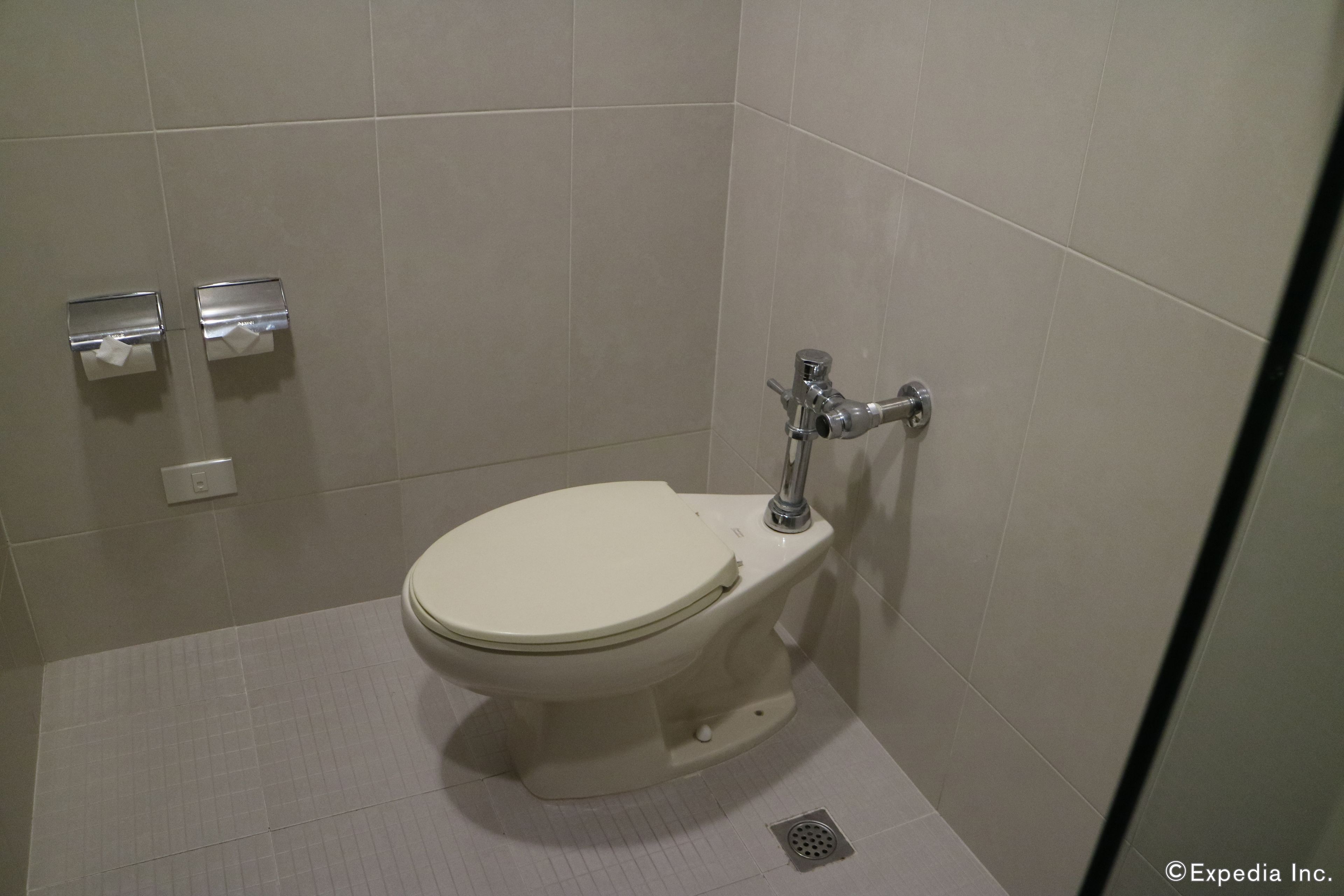 A small, modern bathroom with a toilet, a hand dryer, and a paper towel dispenser.