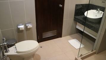 A bathroom with a toilet, sink, and shower area.