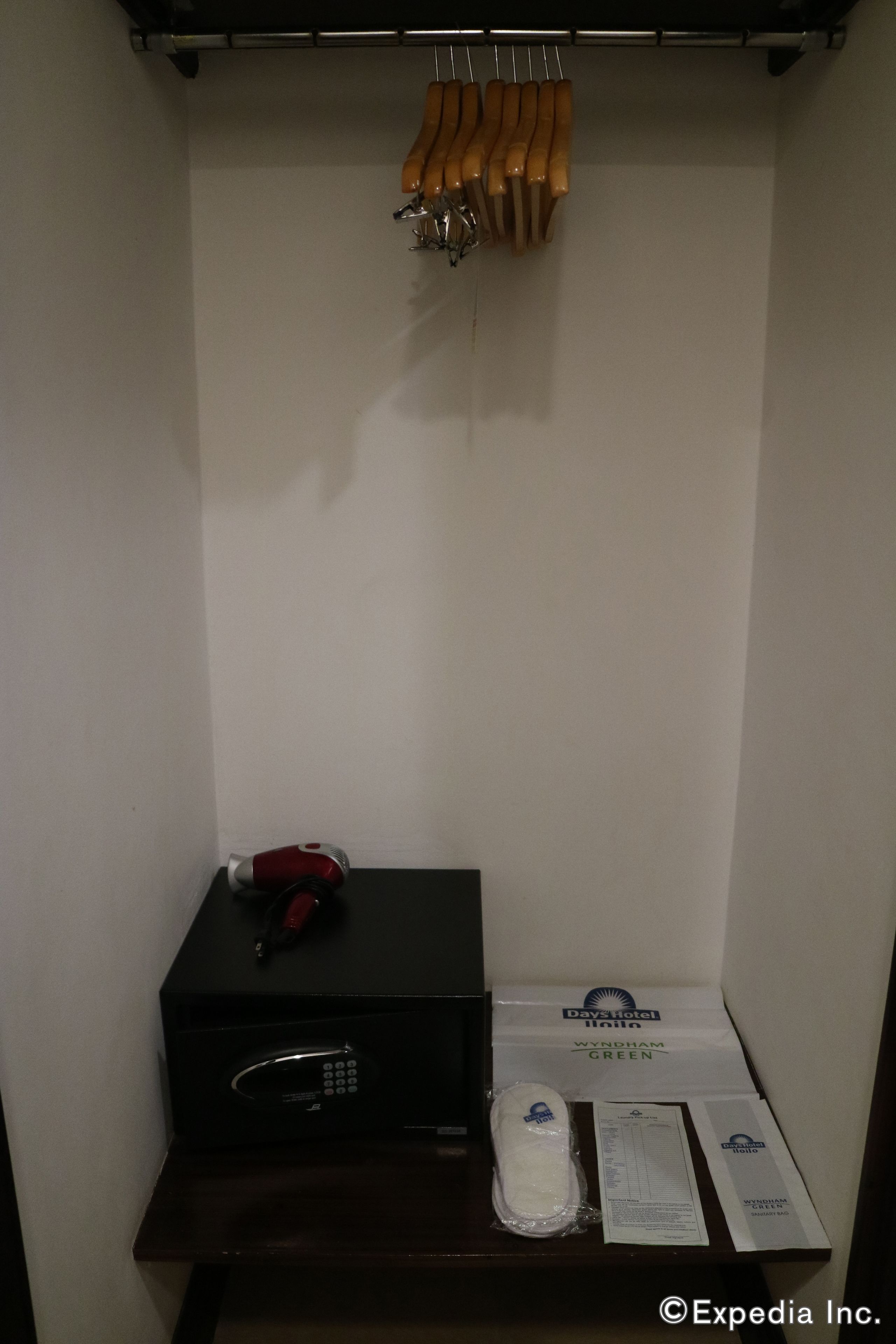 A hotel room with a minibar, a set of keys, a red pen, and a hotel brochure on a small table.
