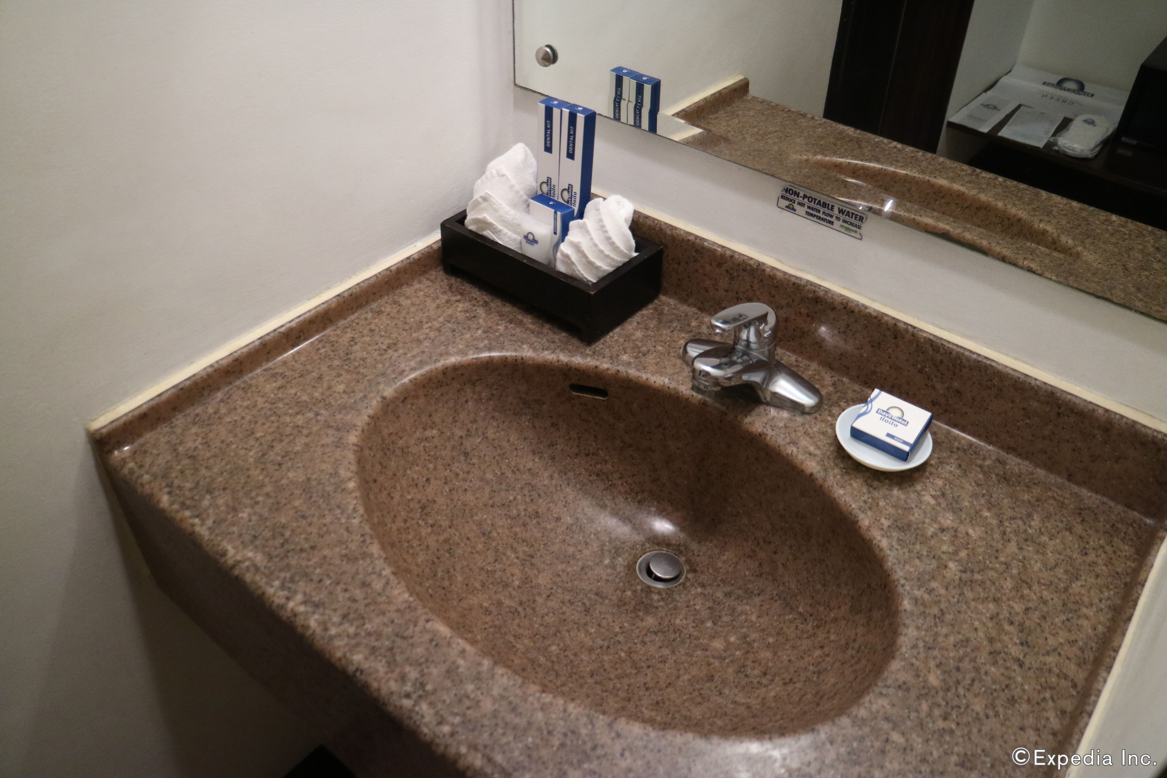 A bathroom sink with a granite countertop, a mirror above, and a soap dish.