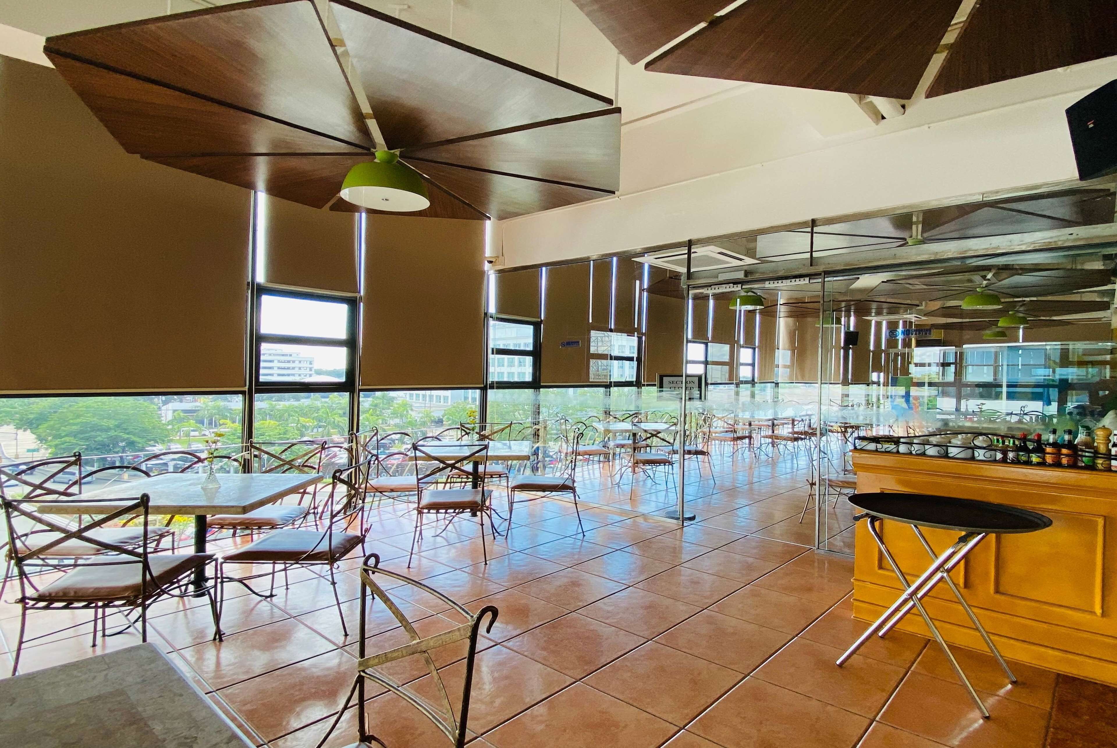 A spacious indoor area with tables and chairs, large windows, and a bar area.