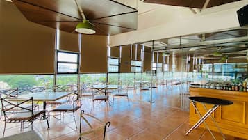 A spacious indoor area with tables and chairs, large windows, and a bar area.