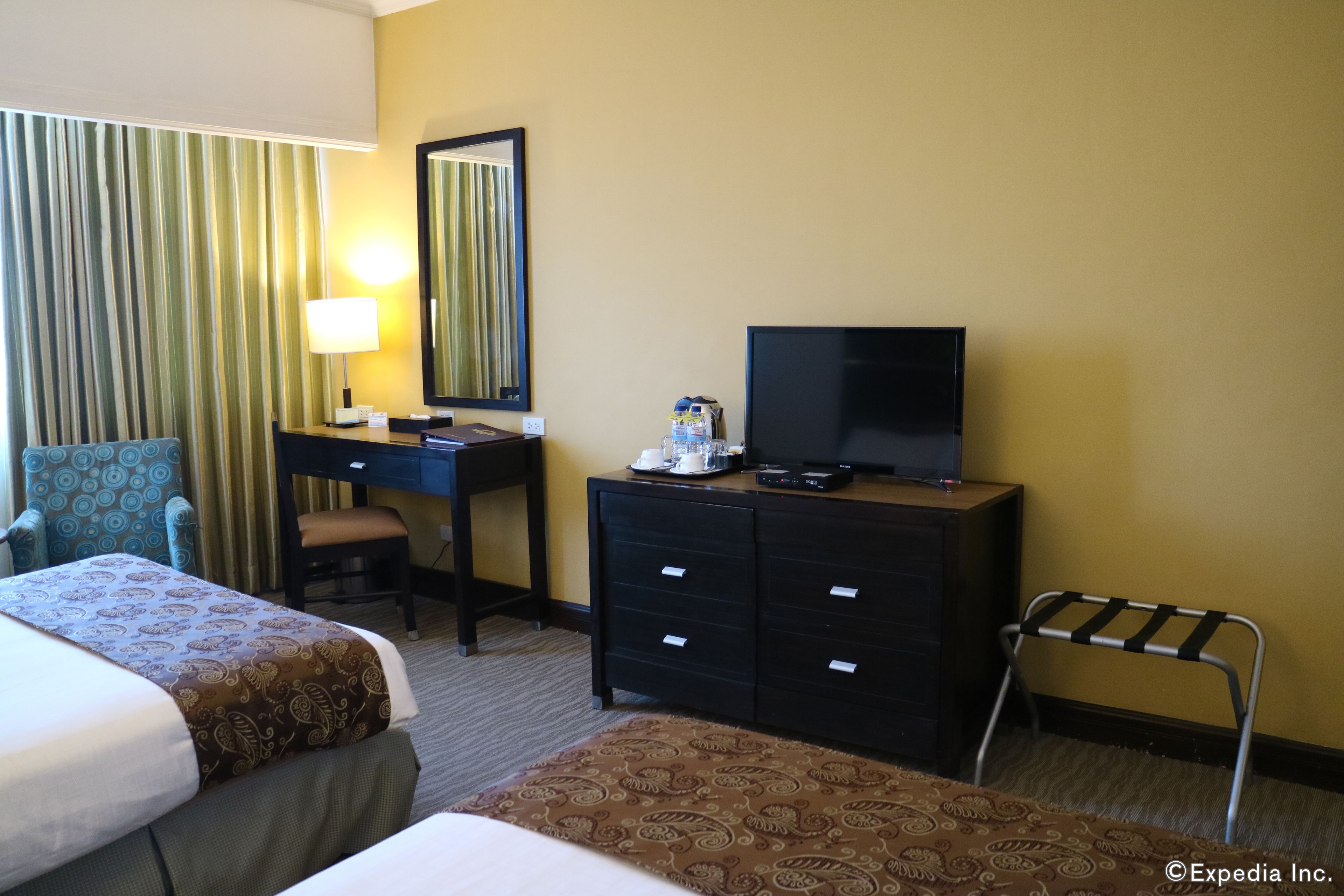 Habitación de hotel con dos camas, un escritorio con ordenador, televisor y una mesita con lámpara.