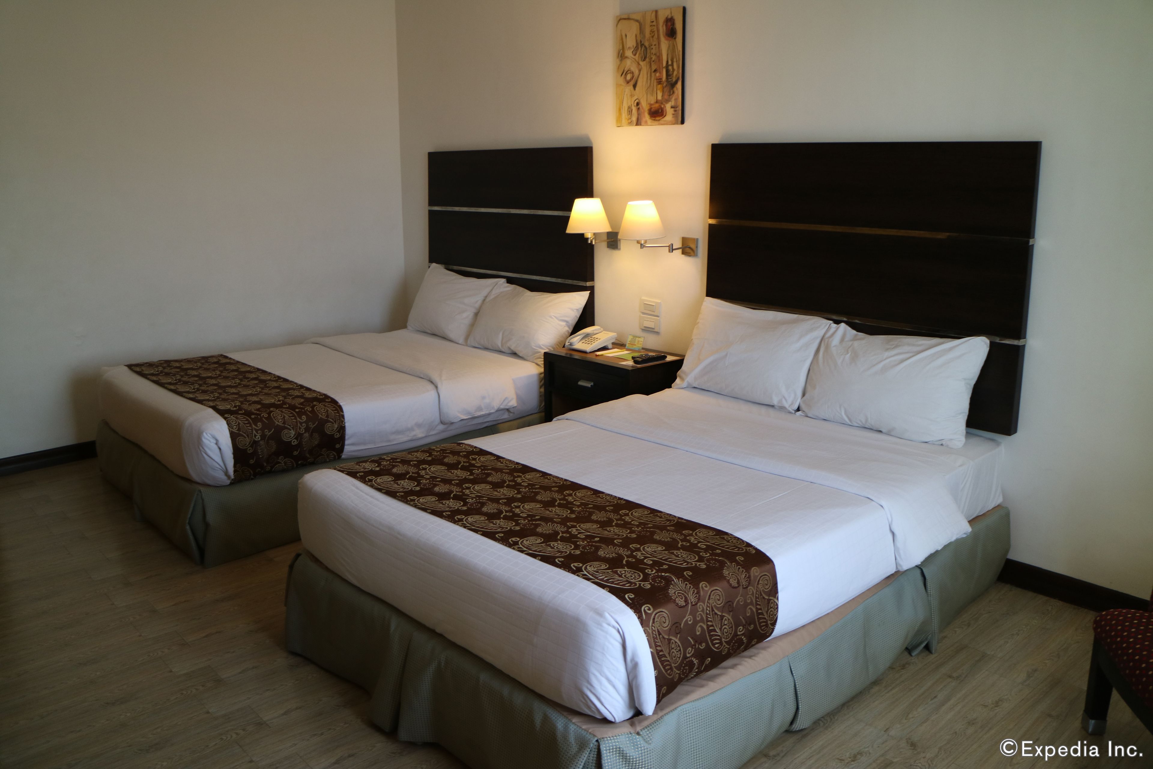 A hotel room with two beds, each with a headboard, bedside tables with lamps, and a telephone.