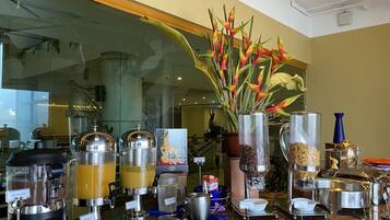 Un buffet proposant différents distributeurs de boissons et de nourriture, avec des étiquettes indiquant le chocolat chaud, le jus d’orange et le jus de mangue.