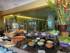 A buffet with various food options including fresh fruit, salads, and dips.