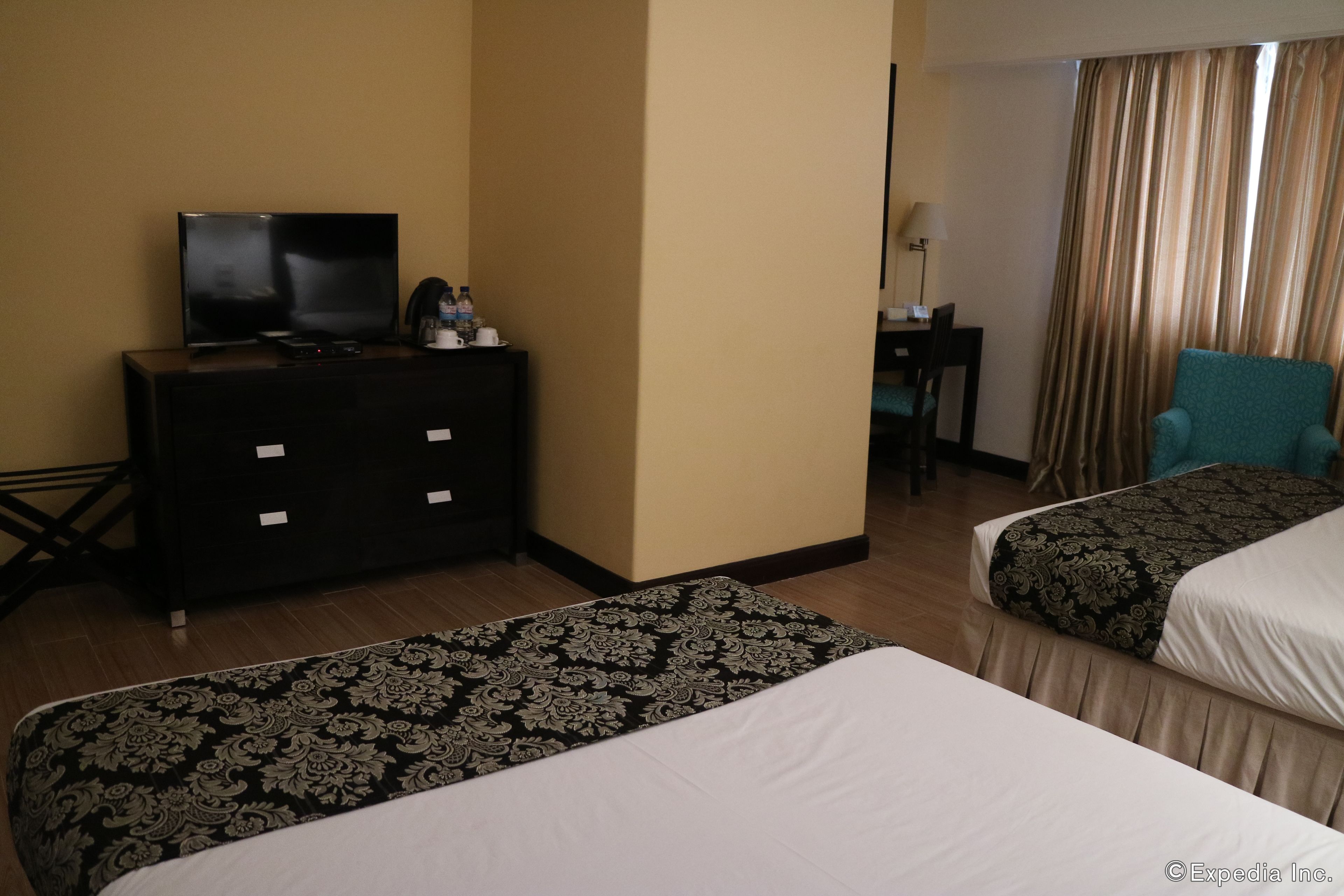 Habitación de hotel con dos camas, un televisor en una cómoda, un escritorio con lámpara y una silla.