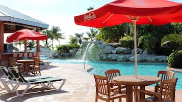A poolside area with lounge chairs, a table, and a red umbrella.