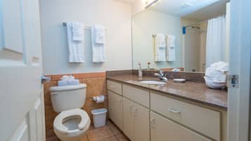 A bathroom with a toilet, sink, mirror, and towel rack.