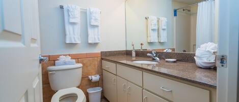 A bathroom with a toilet, sink, mirror, and towel rack.