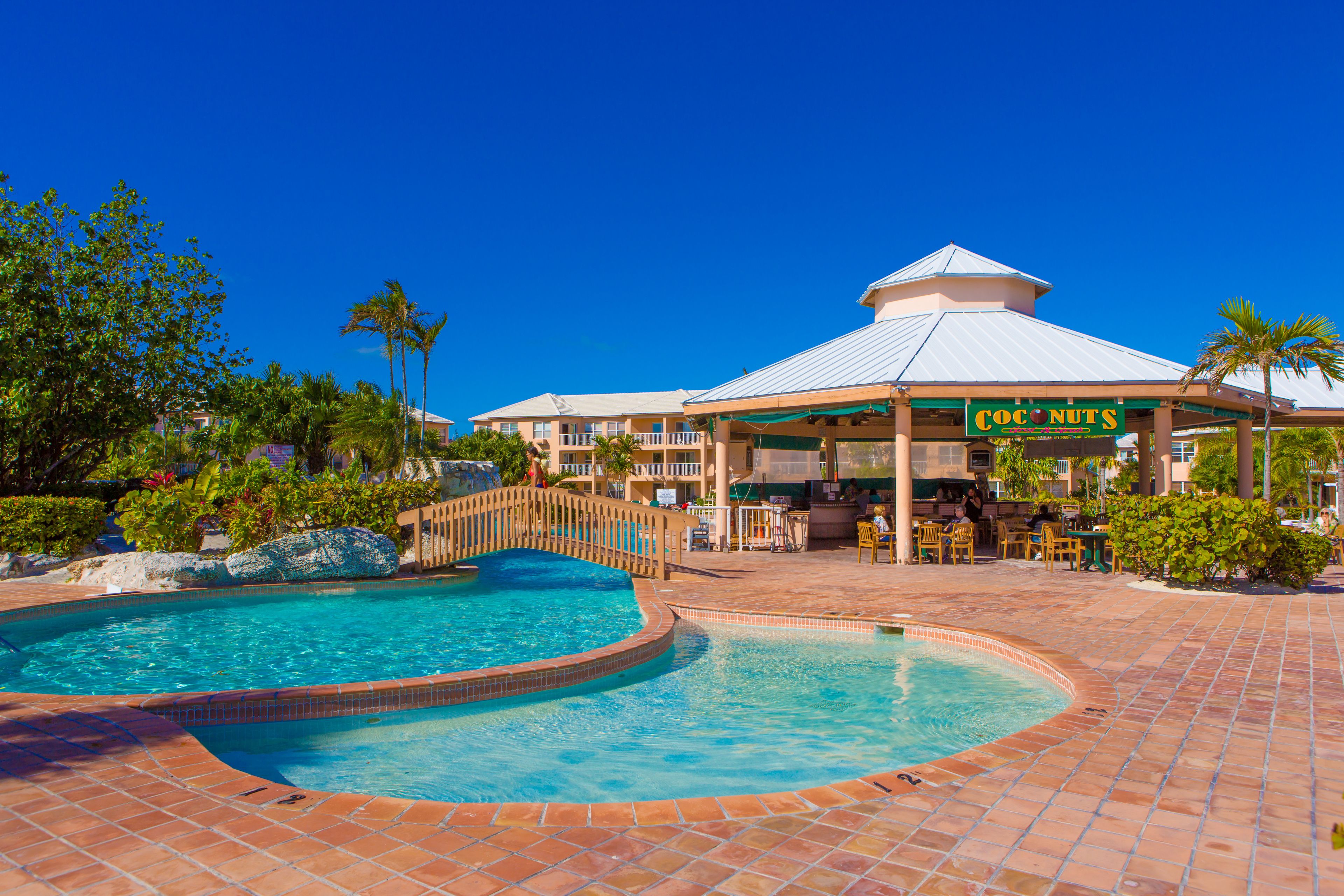 A resort with a pool, a restaurant named 'Coconuts', and a covered seating area.