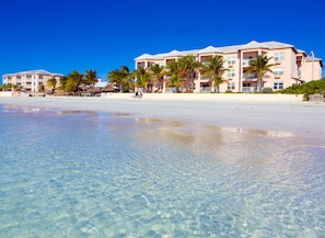 A beachfront hotel with clear blue waters, palm trees, and a sandy beach. - Island Seas Resort (Freeport)