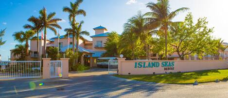 A resort entrance with a sign reading "Island Seas Resort," palm trees, and a gated driveway.