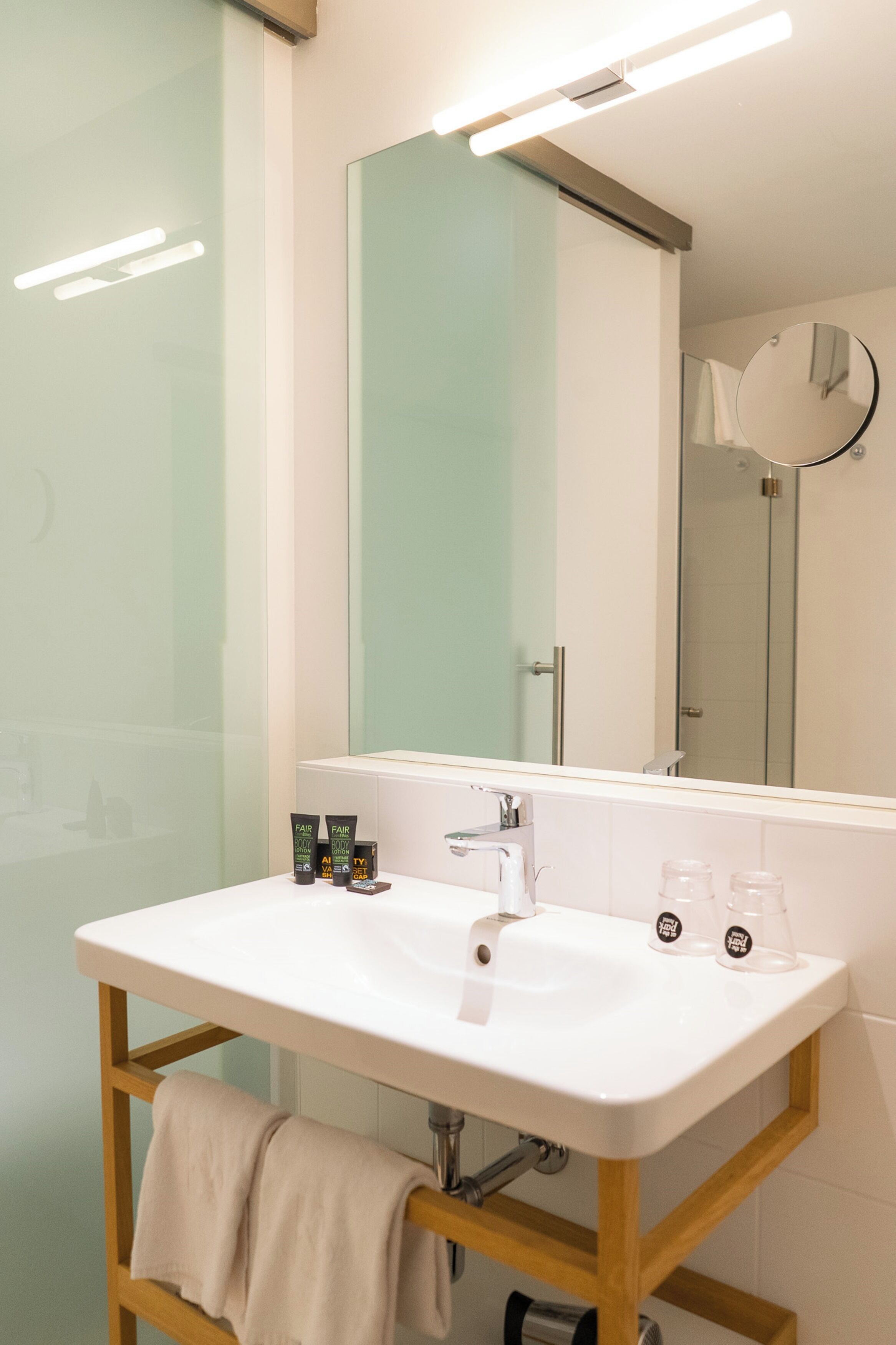 A bathroom with a white sink, mirror, and glass shower enclosure.
