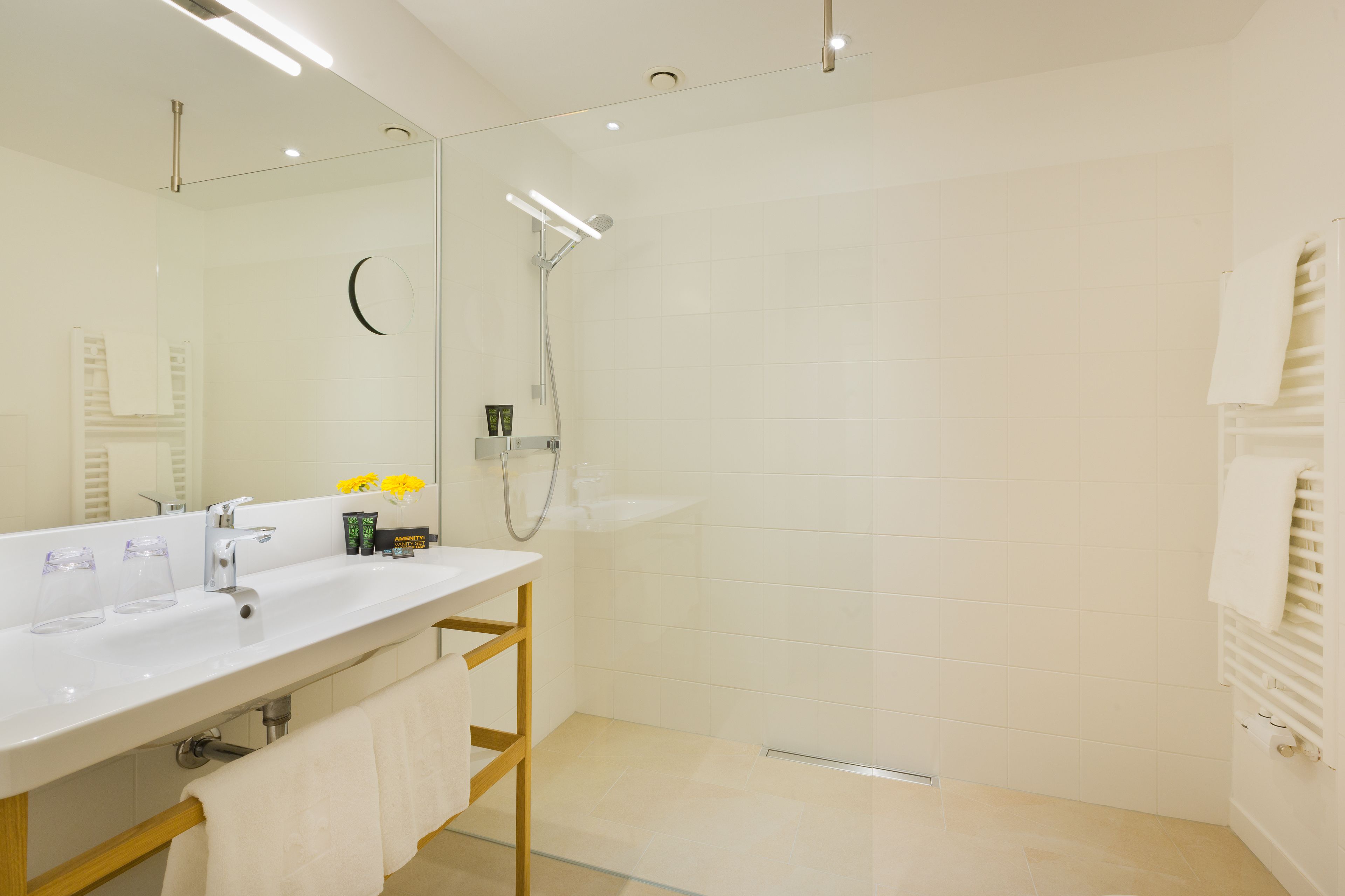 A modern bathroom with a white sink, mirror, and shower.