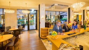 A modern restaurant interior with wooden tables, chairs, and a bar area. - At the Park Hotel (Baden)