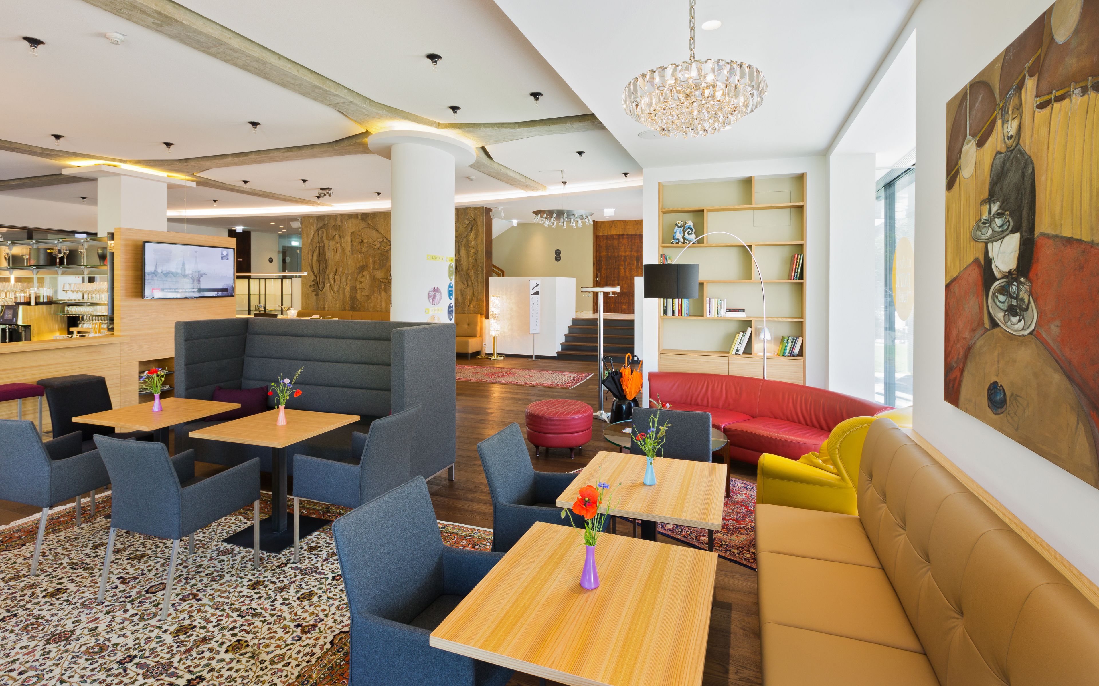 En moderne hotellobby med siddeområder, en bar og en trappe, der fører op til etagen over.