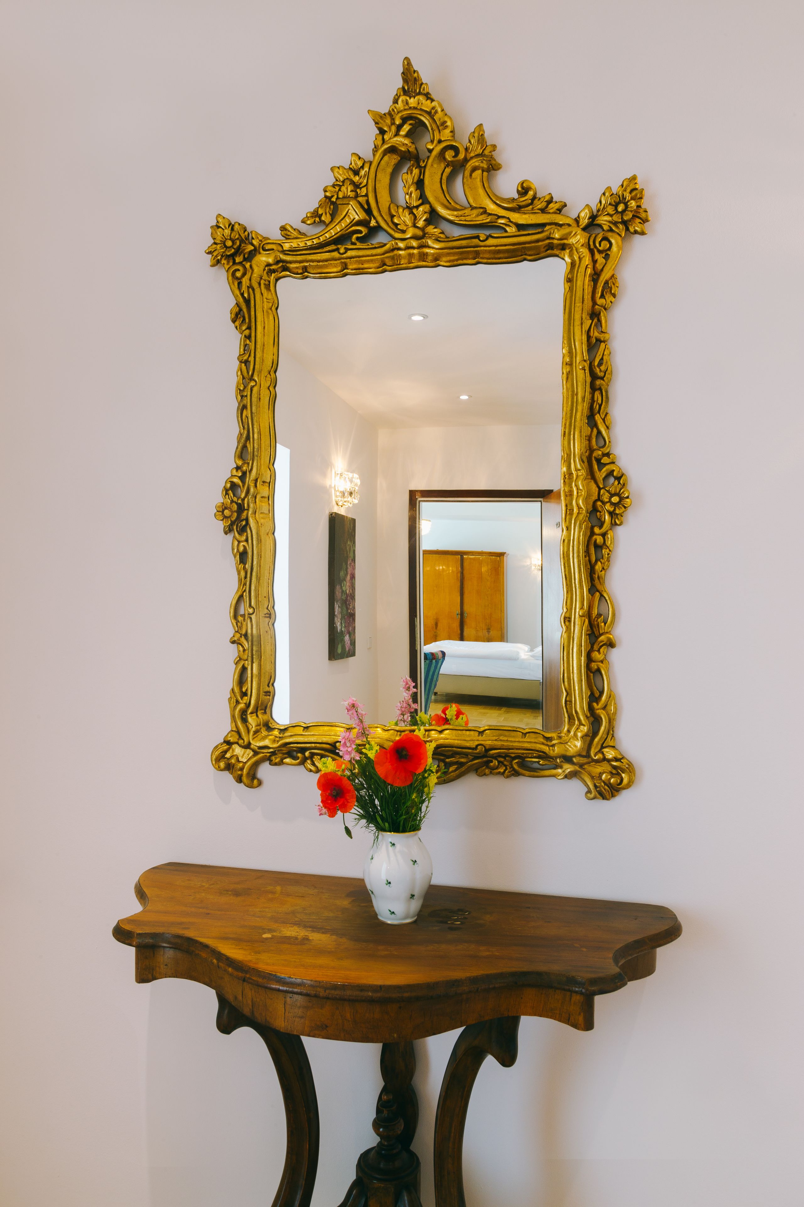 A mirror with an ornate gold frame on a wooden console table.