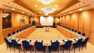 A conference room with a long table, chairs, a podium, and a projector screen.